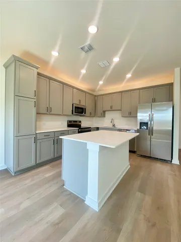 a large kitchen with kitchen island a sink a center island stainless steel appliances and cabinets