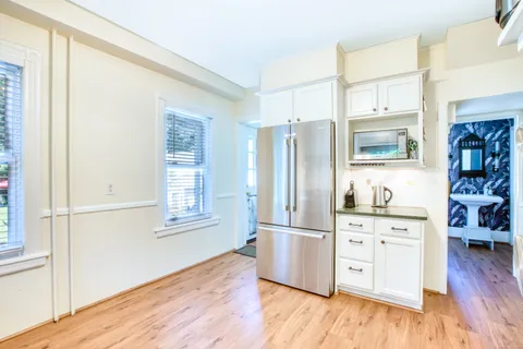 a kitchen with stainless steel appliances a refrigerator cabinets and wooden floor