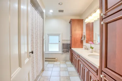 a bathroom with a double vanity sink a large mirror and a bathtub