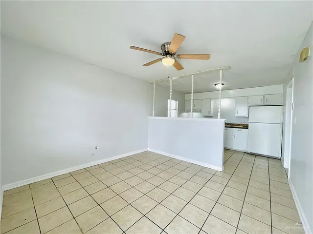 a view of an empty room and chandelier fan