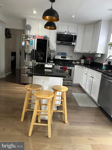 a kitchen with stainless steel appliances kitchen island granite countertop a sink a stove a table and chairs