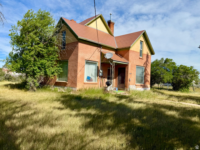Brick exterior residence featuring a front porch with an awning, a gabled roofline, and multiple windows