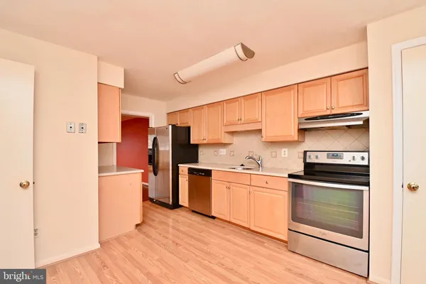 a kitchen with stainless steel appliances granite countertop a refrigerator a stove and a sink