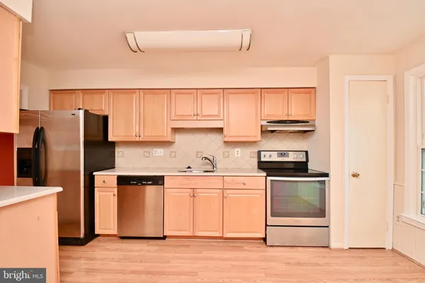 a kitchen with stainless steel appliances a stove a refrigerator a sink and white cabinets