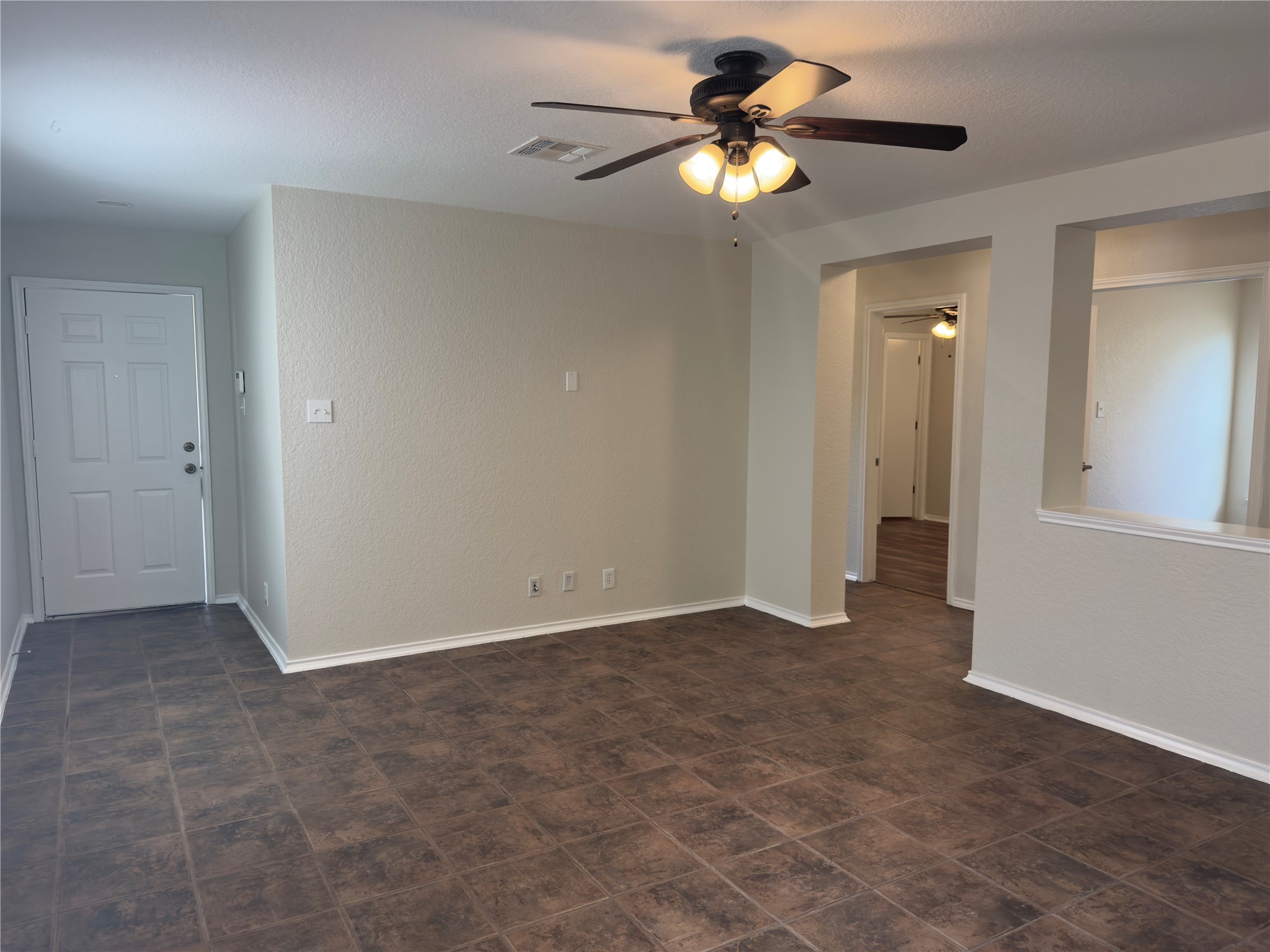 255 Myrtle Street Kyle, TX 78640 - Photo 11 of 31 Spacious room with dark tile flooring, neutral wall tones, white trim, and a ceiling fan with integrated lighting