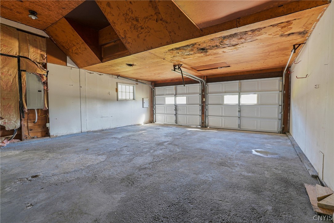 7779 Bell Road North Rome, NY 13440 - Photo 33 of 38 A spacious garage interior highlights concrete flooring and dual bay doors under wood-paneled ceilings.