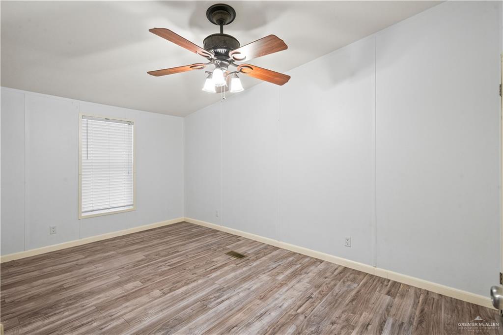 215 South Valley View Road, Unit 252 Donna, TX 78537 - Photo 11 of 19 Spacious room featuring wood-finish flooring, white walls, and a ceiling fan with integrated lighting
