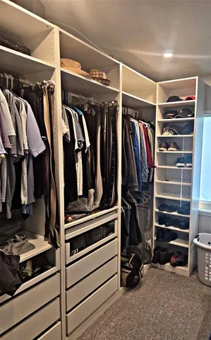 a view of walk in closet with clothes and shoes
