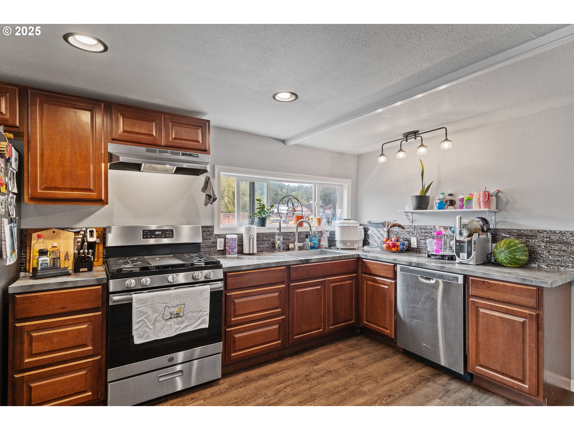 1434 Maryland Avenue Myrtle Point, OR 97458 - Photo 6 of 24 a kitchen with stainless steel appliances granite countertop a stove a sink dishwasher and cabinets with wooden floor