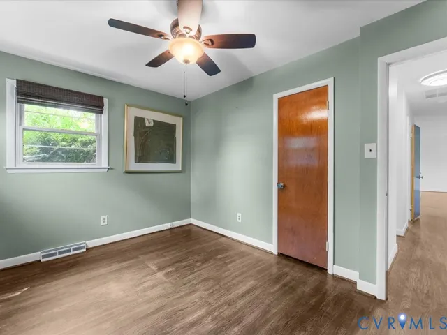 an empty room with wooden floor ceiling fan and windows