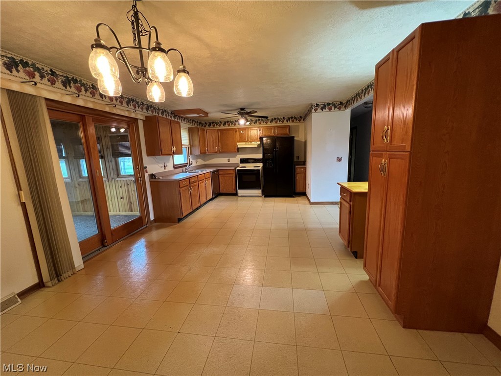 9066 Crow Road Litchfield, OH 44253 - Photo 15 of 28 Kitchen with ceiling fan with notable chandelier, light tile flooring, hanging light fixtures, white range, and black fridge with ice dispenser