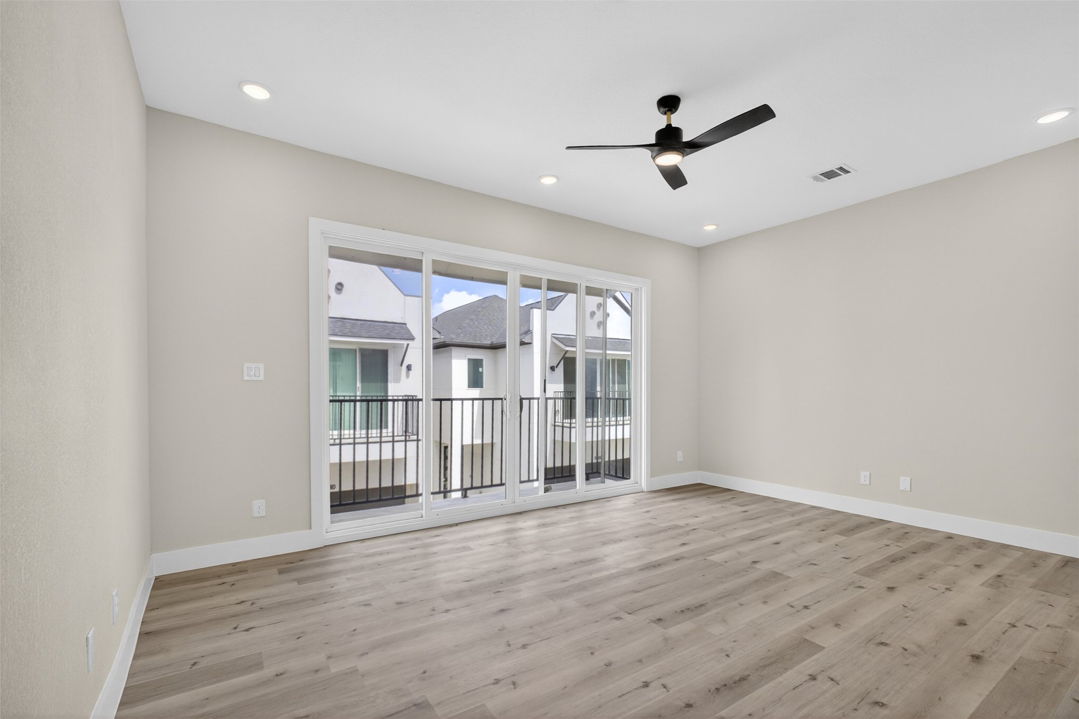 5906 St Augustine Street, Unit F Houston, TX 77021 - Photo 4 of 34 Primary bedroom with wide sliding glass doors, a modern ceiling fan, and direct access to a private balcony.