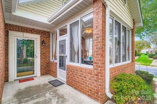 a view of a brick house with large windows and a large tree