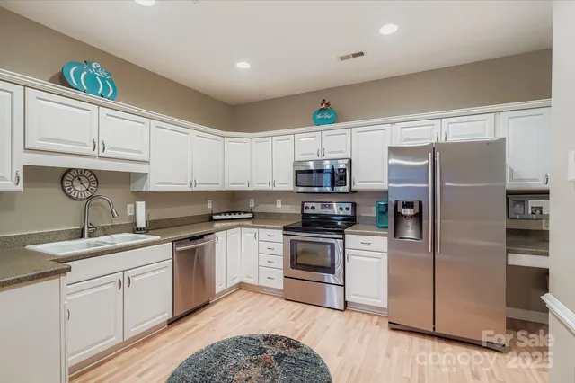 a kitchen with stainless steel appliances granite countertop a sink stove refrigerator and cabinets
