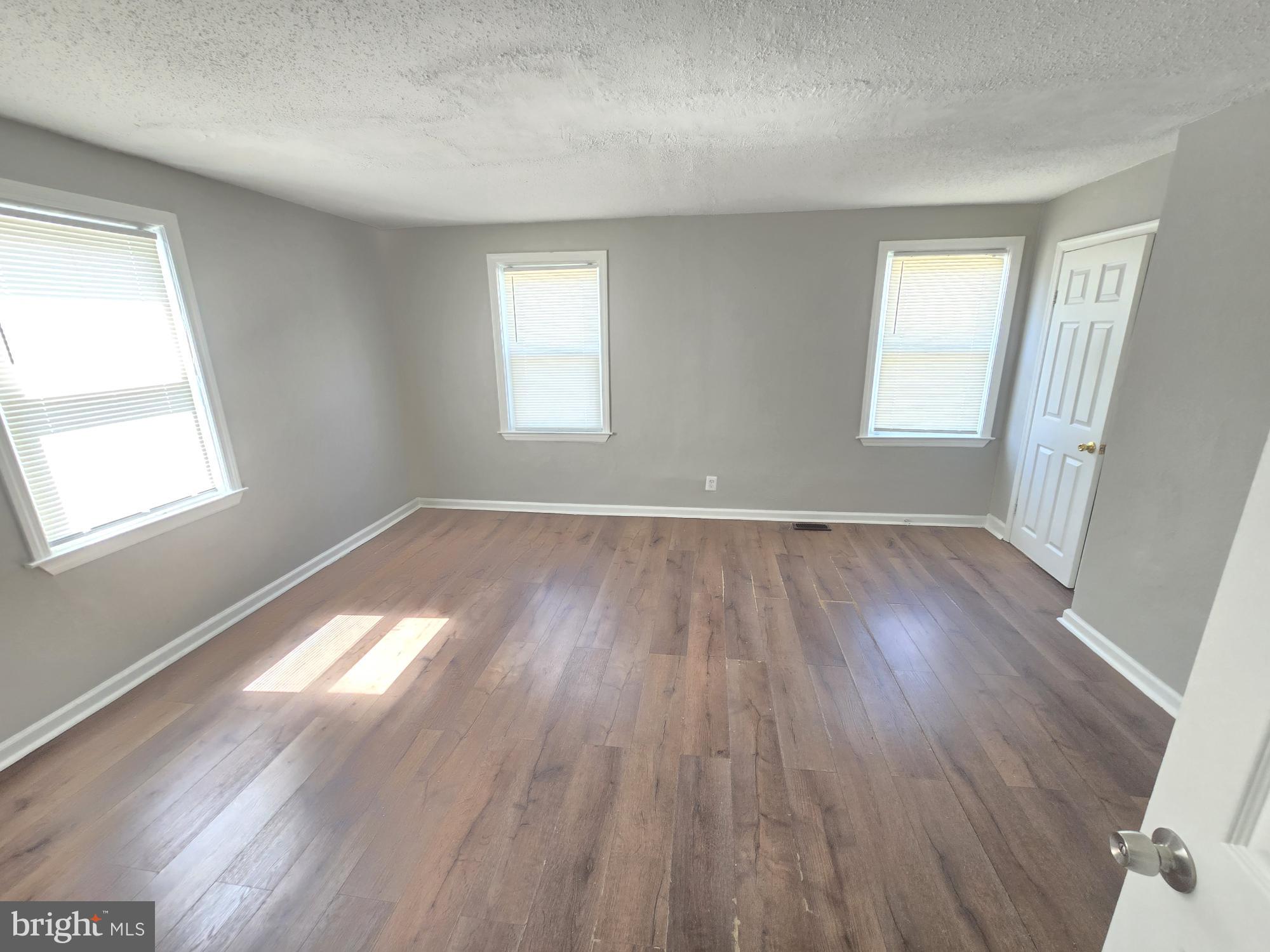 5413 Belle Vista Avenue Baltimore, MD 21206 - Photo 11 of 14 an empty room with wooden floor and windows
