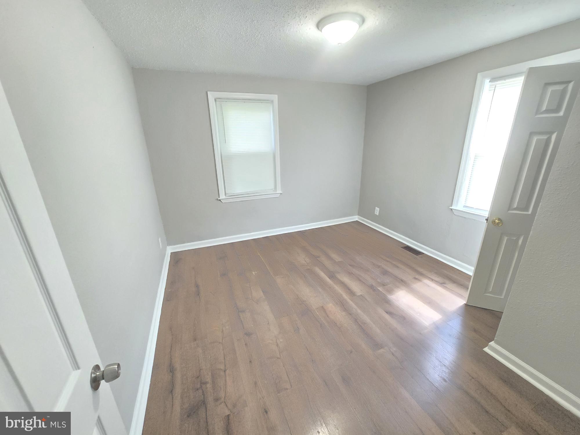 5413 Belle Vista Avenue Baltimore, MD 21206 - Photo 13 of 14 an empty room with wooden floor and windows