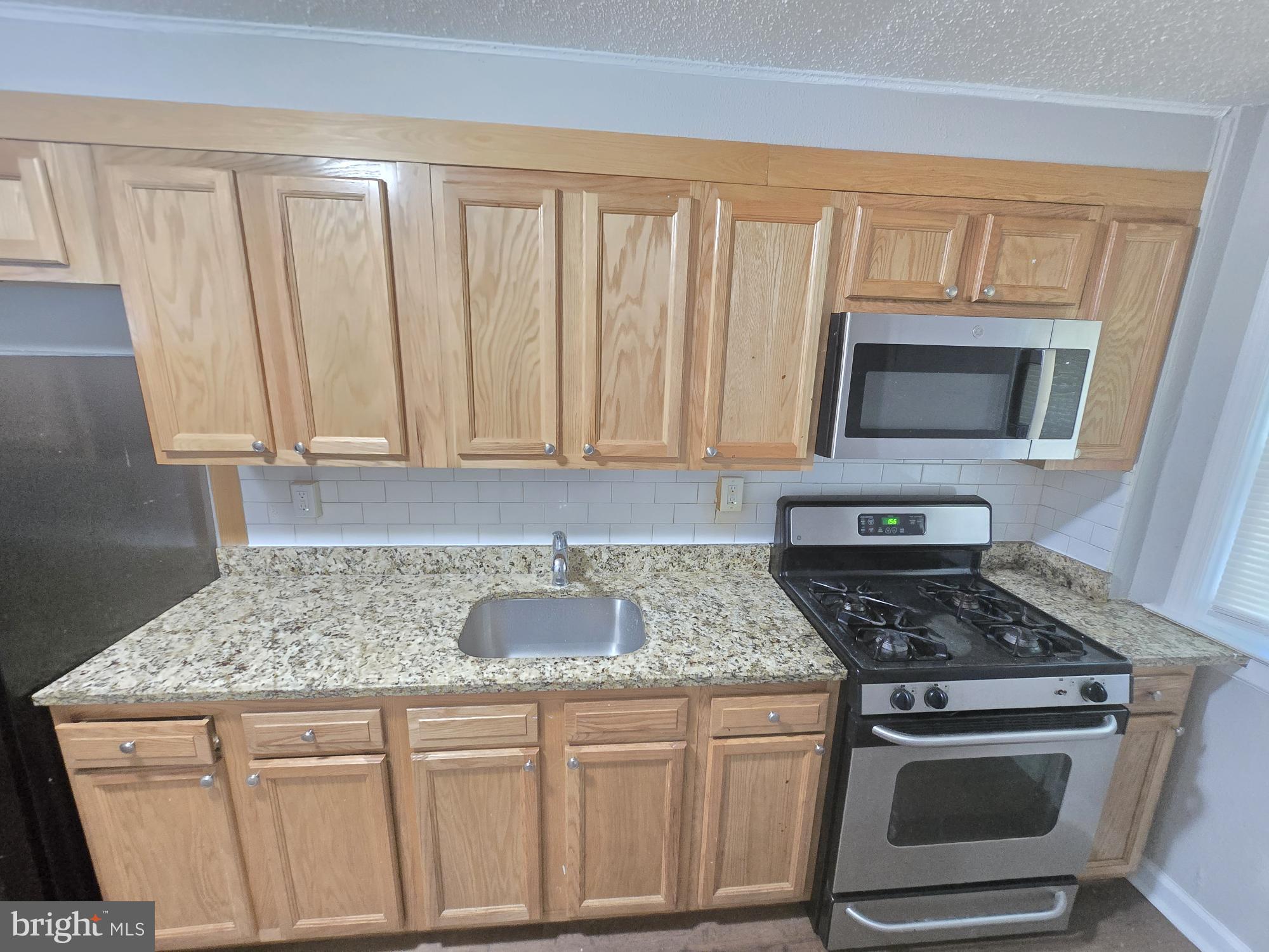 5413 Belle Vista Avenue Baltimore, MD 21206 - Photo 4 of 14 a kitchen with granite countertop a stove sink and microwave