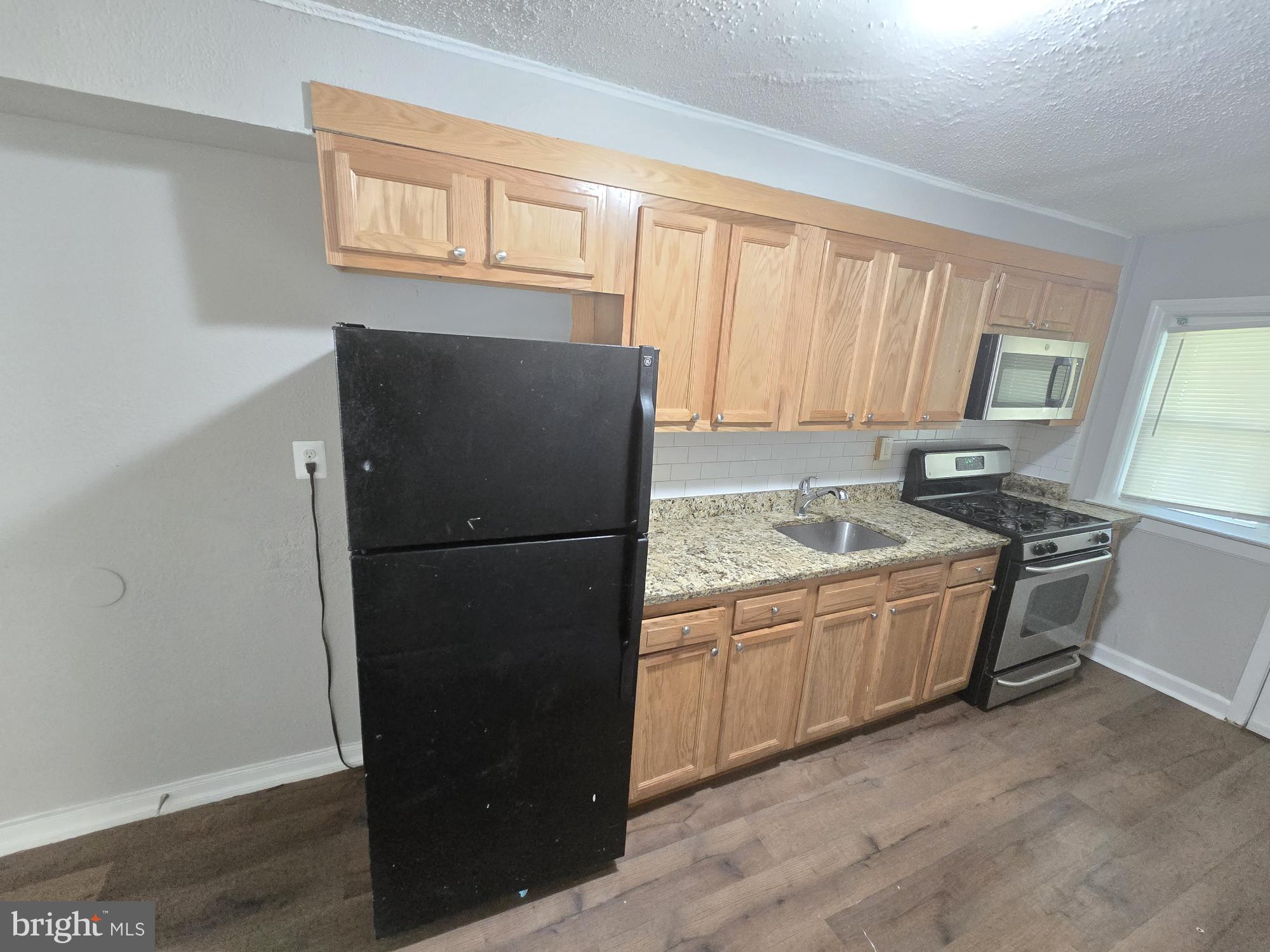 5413 Belle Vista Avenue Baltimore, MD 21206 - Photo 6 of 14 a kitchen with stainless steel appliances granite countertop a refrigerator and a sink