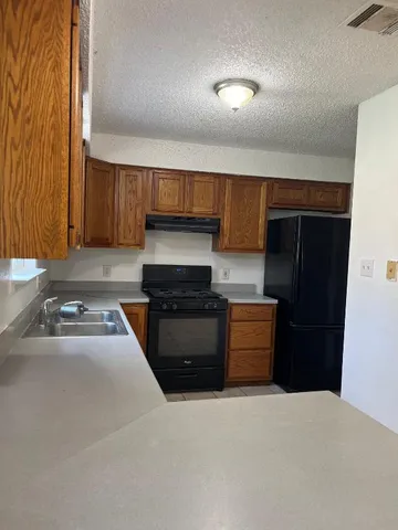 a kitchen with granite countertop a refrigerator and a stove top oven