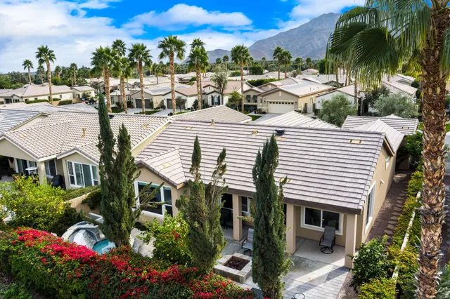 a front view of a house with a garden and trees