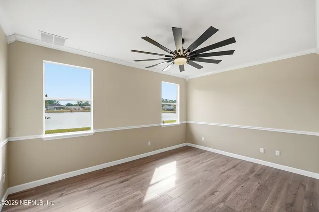 an empty room with wooden floor and windows