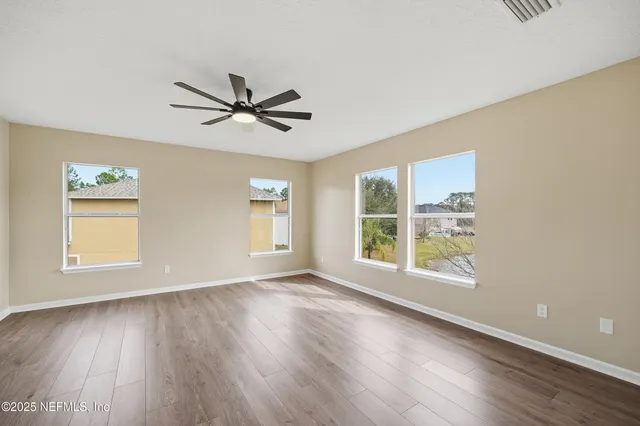 an empty room with wooden floor and windows