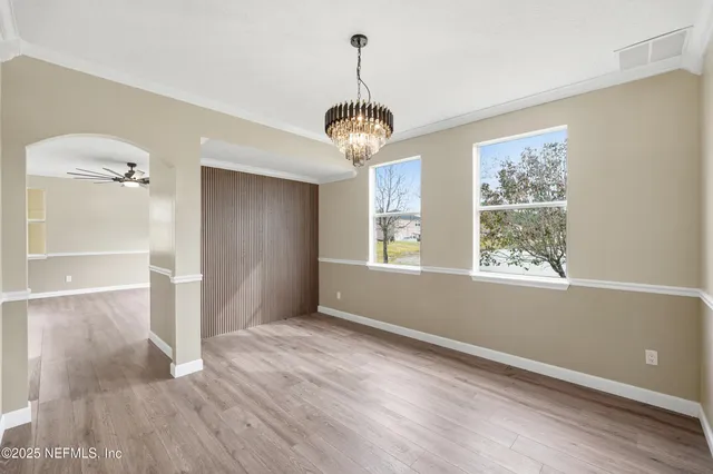 a view of a room with wooden floor chandelier and windows