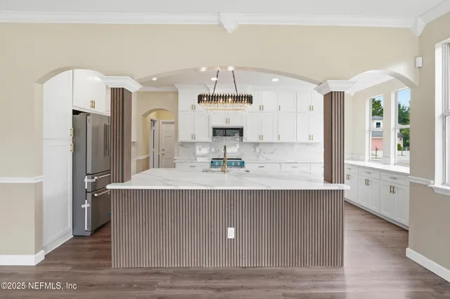 a view of living room with granite countertop kitchen island stainless steel appliances wooden floor and living room view