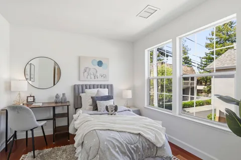 a bedroom with a bed a mirror and a large window