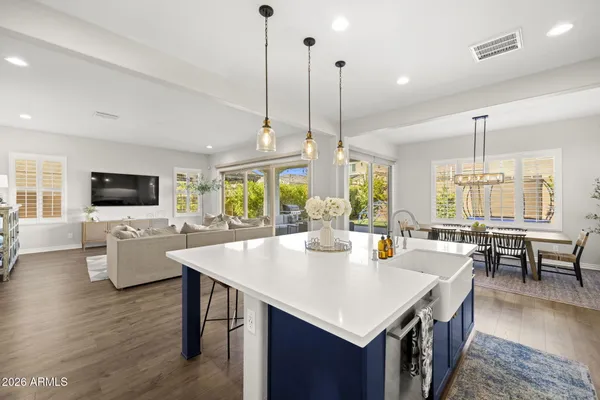 a kitchen with stainless steel appliances granite countertop a stove top oven a sink dishwasher a dining table and chairs with wooden floor