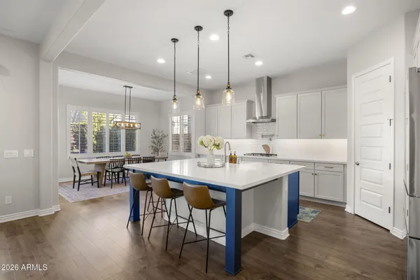 a kitchen with kitchen island a dining table chairs sink and wooden floor
