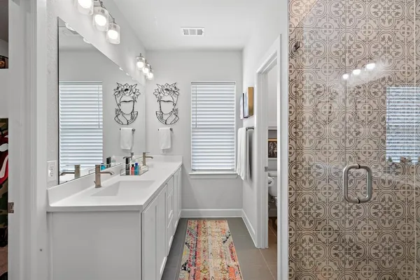 a bathroom with a sink a toilet a mirror and shower