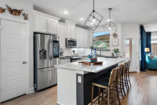 a kitchen with stainless steel appliances a dining table chairs refrigerator and microwave