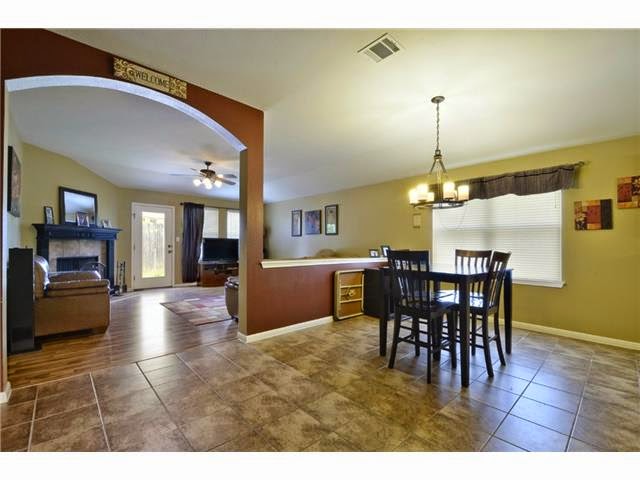 11612 Timber Heights Drive Austin, TX 78754 - Photo 19 of 28 These walls have been painted with neutral color. An inviting dining space with tile flooring transitions seamlessly into a living area with warm wood floors and a fireplace.