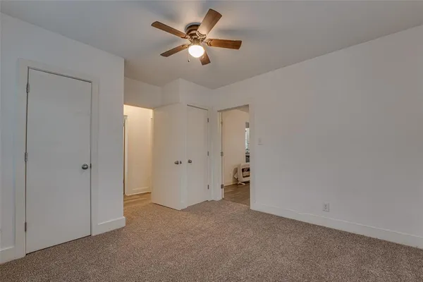 an empty room with chandelier fan and windows