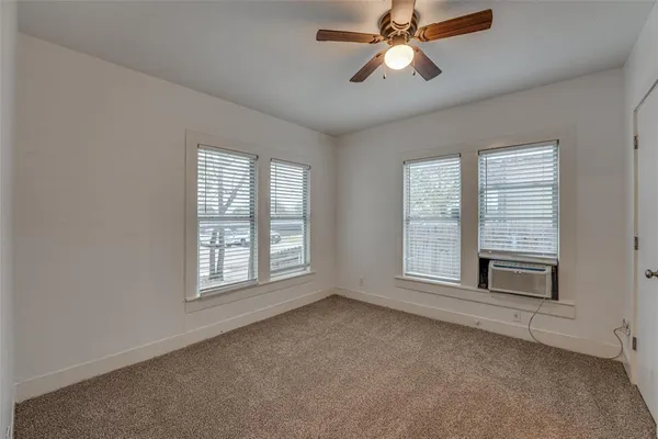 an empty room with chandelier fan and windows