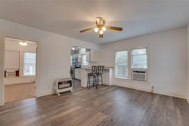 a view of a livingroom with furniture hardwood floor a ceiling fan and windows