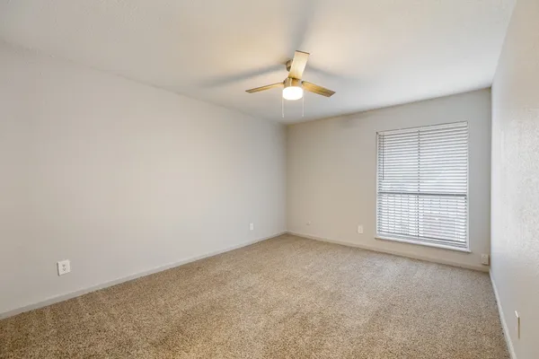 an empty room with windows and ceiling fan