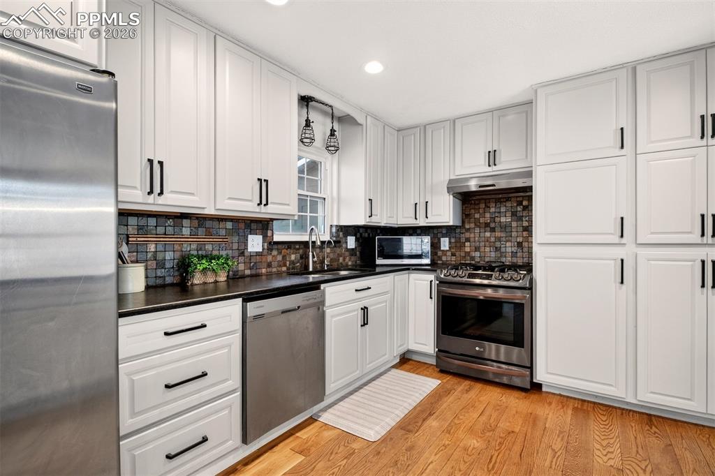 5226 Rocking R Drive Colorado Springs, CO 80915 - Photo 17 of 46 a kitchen with granite countertop white cabinets and stainless steel appliances