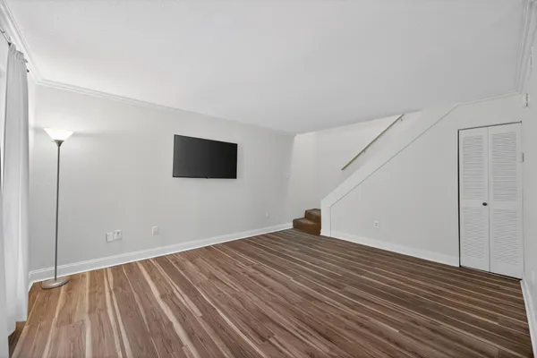 a view of an empty room with wooden floor and a window