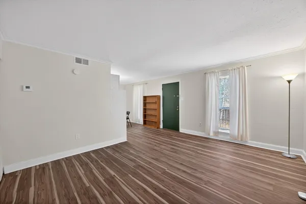 a view of an empty room with wooden floor and window