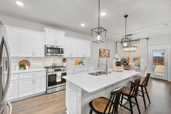 a kitchen with stainless steel appliances kitchen island granite countertop a stove a sink a dining table and chairs with wooden floor