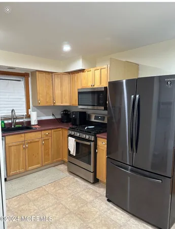 a kitchen with granite countertop stainless steel appliances a refrigerator cabinets and a window