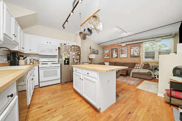 a kitchen with cabinets wooden floor and stainless steel appliances