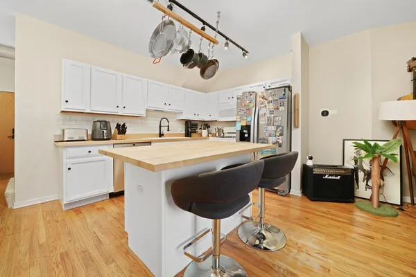a kitchen with stainless steel appliances granite countertop a refrigerator a stove a sink dishwasher and white cabinets with wooden floor