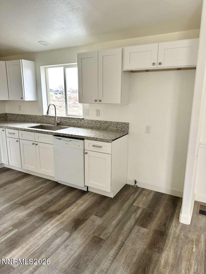 6255 Sierra Way Fallon, NV 89406 - Photo 5 of 25 a kitchen with granite countertop a sink cabinets and wooden floor