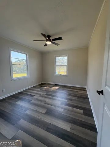 a view of an empty room with a window and wooden floor