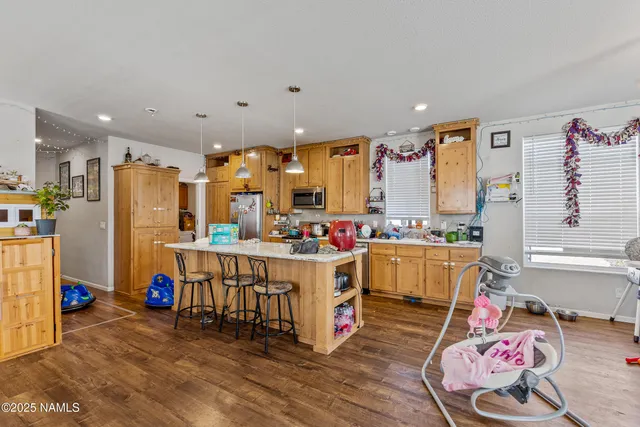 a view of kitchen with stainless steel appliances wooden floor and stove top oven