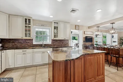 a kitchen with stainless steel appliances granite countertop a stove top oven a sink a dining table and chairs
