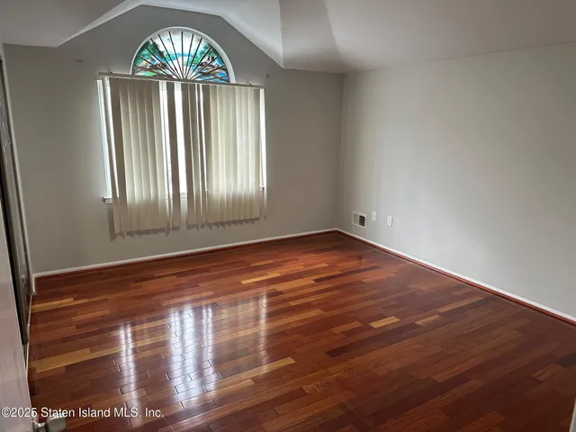 an empty room with wooden floor and a window